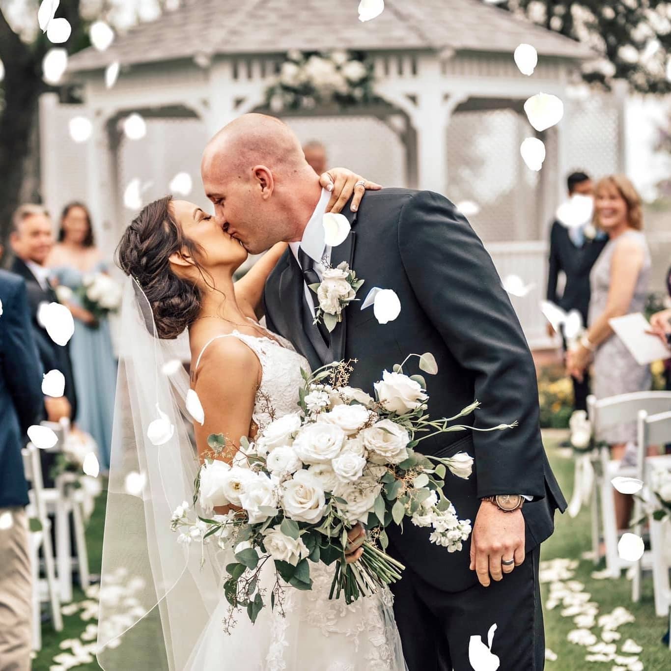 bride and groom kissing at gazebo during outdoor wedding ceremony